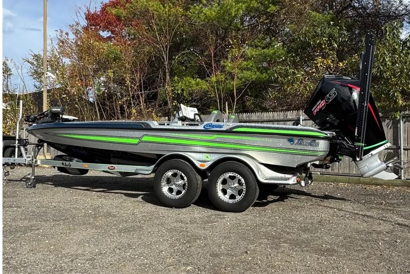 Slide: The Image of 2021 Bass Cat Cougar FTD boat on trailer, parked outdoors with trees in background. - 4