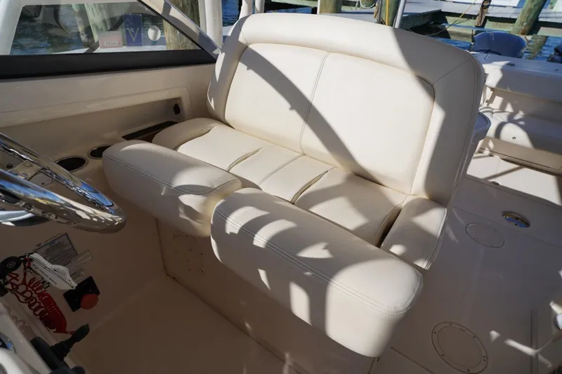 Slide: The Image of 2015 Grady-White Freedom 307 boat interior with cream leather seating and steering wheel. - 19