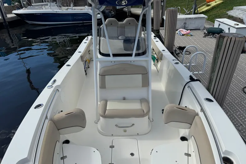Slide: The Image of 2018 NauticStar 2602 Legacy boat with beige seating, docked at a marina. - 10