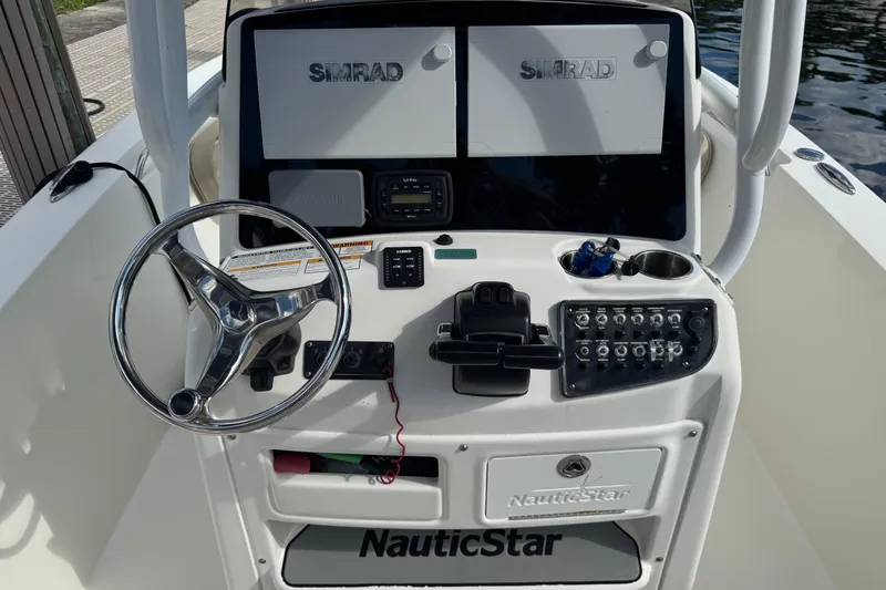 Slide: The Image of 2018 NauticStar 2602 Legacy boat dashboard with steering wheel and Simrad displays. - 7