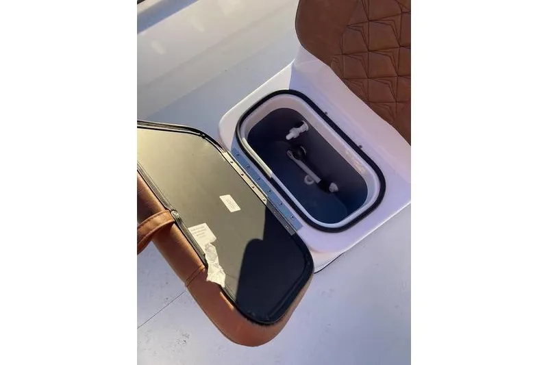 Slide: The Image of Open storage compartment in 2026 Avid 18 Rogue CC boat with brown leather seat. - 10