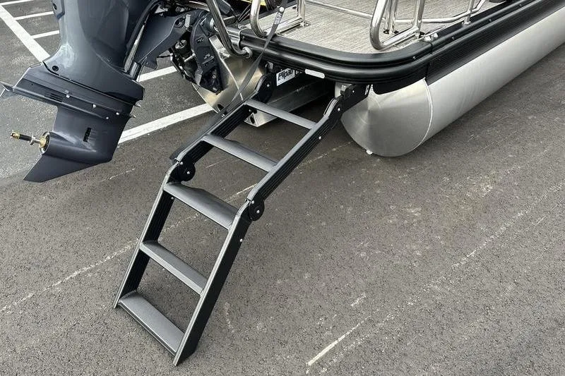 Slide: The Image of 2026 Bennington M Quad Bench 24 MSL boat with ladder and motor on asphalt. - 16