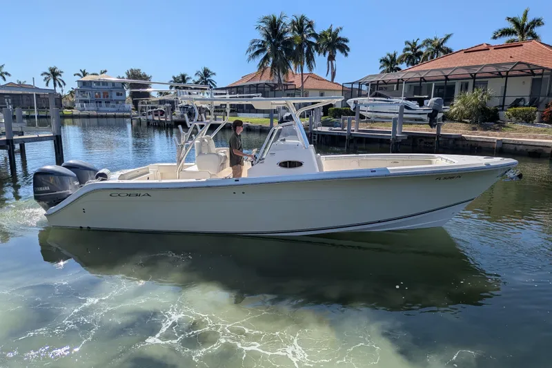 The Image of 2013 Cobia 296 Center Console boat on calm water near waterfront homes. - 0