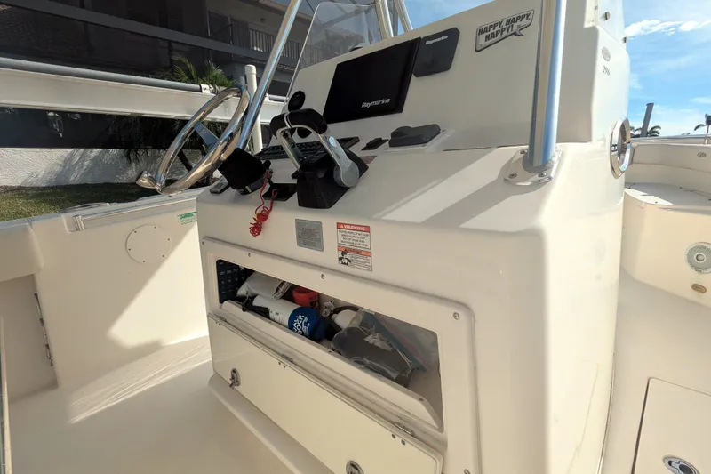 Slide: The Image of 2013 Cobia 296 Center Console boat helm with steering wheel and storage compartment. - 15