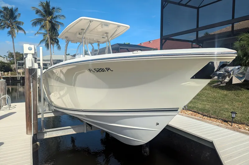 Slide: The Image of 2013 Cobia 296 Center Console boat on lift, surrounded by palm trees and clear skies. - 2