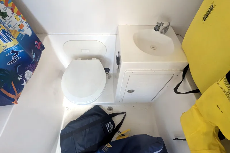 Slide: The Image of 2013 Cobia 296 Center Console boat bathroom with toilet, sink, and life jackets. - 26
