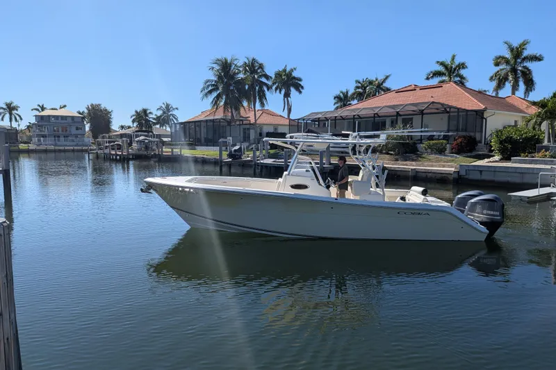 Slide: The Image of 2013 Cobia 296 Center Console boat on a calm waterfront with palm trees. - 3
