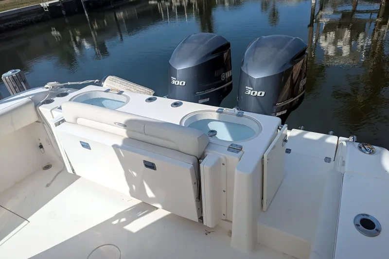 Slide: The Image of 2013 Cobia 296 Center Console boat with dual Yamaha 300 engines, docked by the water. - 31