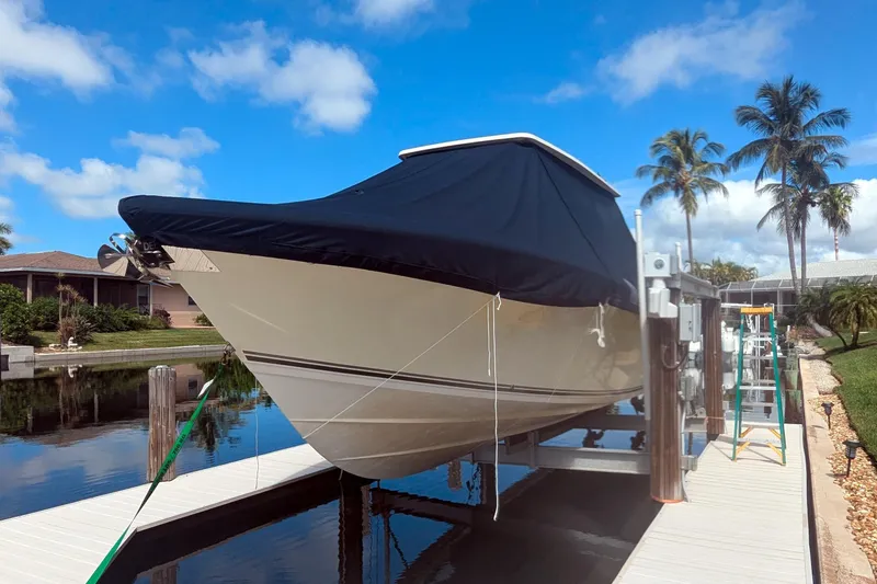 Slide: The Image of 2013 Cobia 296 Center Console boat docked with cover, surrounded by palm trees and blue sky. - 33