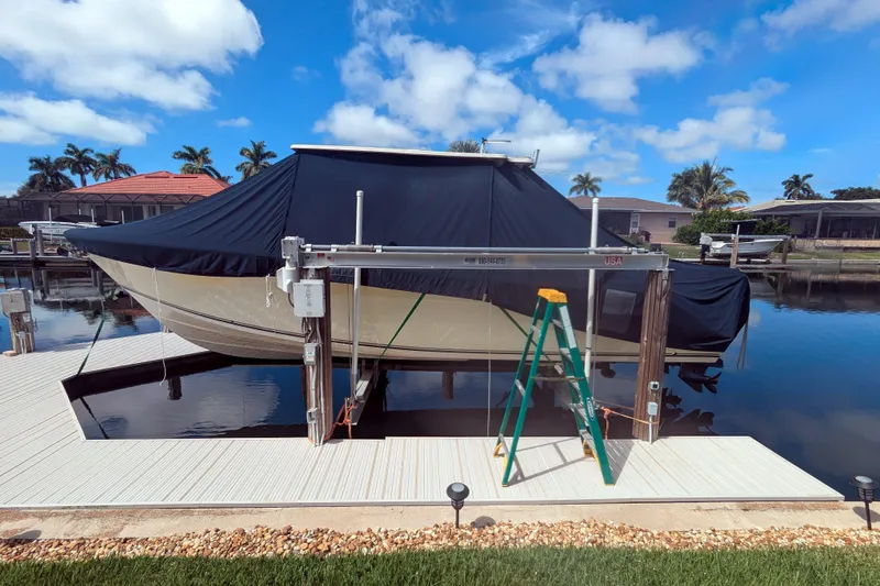 Slide: The Image of 2013 Cobia 296 Center Console boat covered on a lift by a dock. - 34