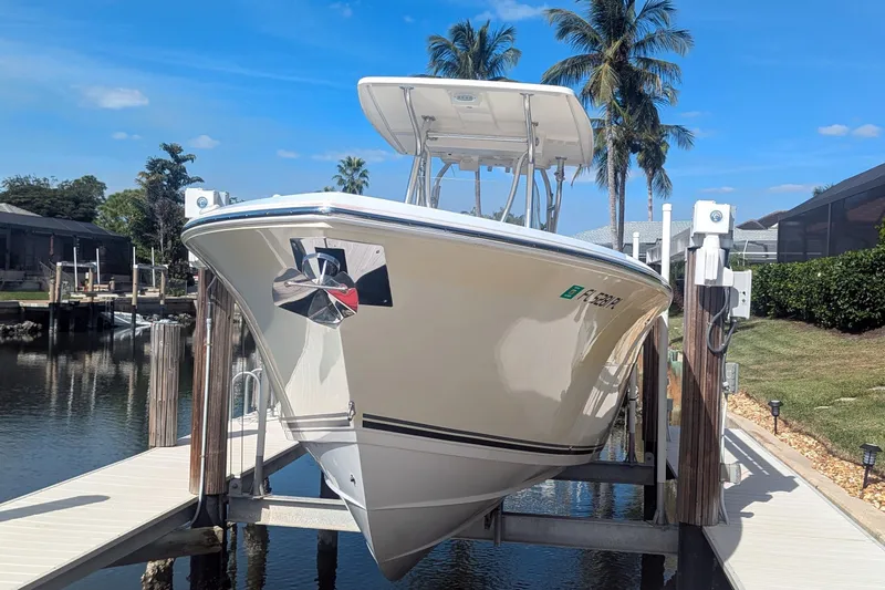 Slide: The Image of 2013 Cobia 296 Center Console boat on lift, docked by palm trees and waterway. - 4