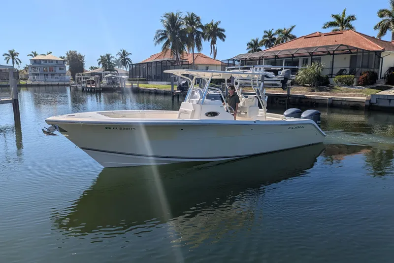 Slide: The Image of 2013 Cobia 296 Center Console boat on calm water with palm trees in the background. - 5