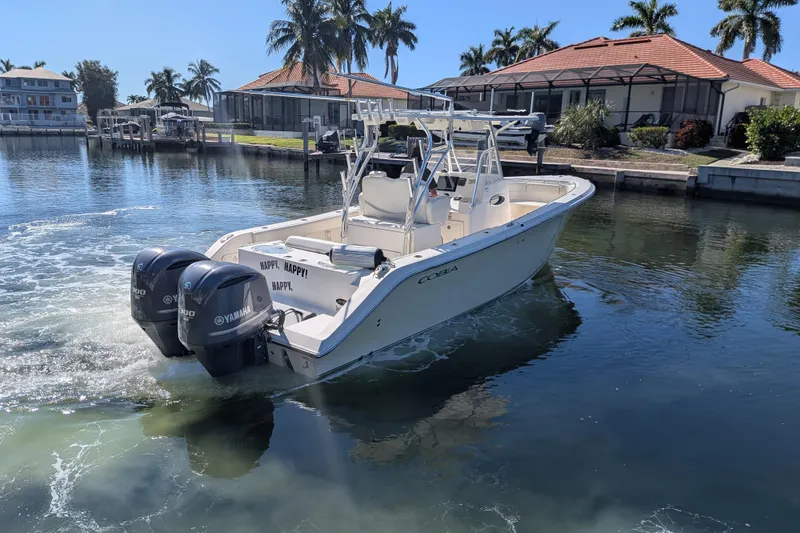 Slide: The Image of 2013 Cobia 296 Center Console boat with twin Yamaha engines on a sunny waterfront. - 8