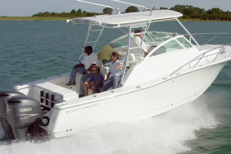 Slide: The Image of 2008 Southport 28 Express boat cruising on a scenic lake with lush green backdrop. - 2