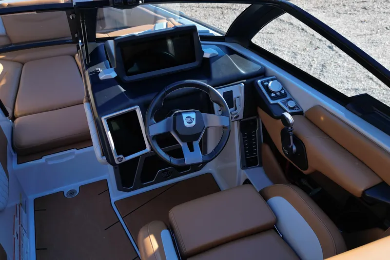 Slide: The Image of 2021 Malibu M220 boat interior with modern dashboard and tan seating. - 11