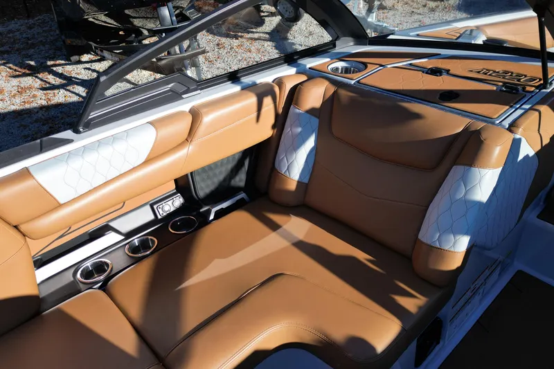 Slide: The Image of 2021 Malibu M220 boat interior with tan and white leather seating, cup holders, and control panel. - 13