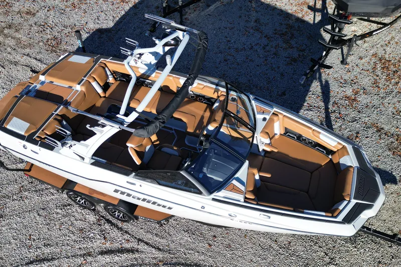 Slide: The Image of Overhead view of a 2021 Malibu M220 boat with tan interior on gravel. - 4