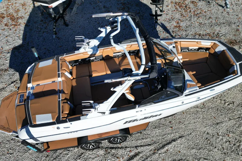 Slide: The Image of 2021 Malibu M220 boat with brown interior, viewed from above on gravel surface. - 6