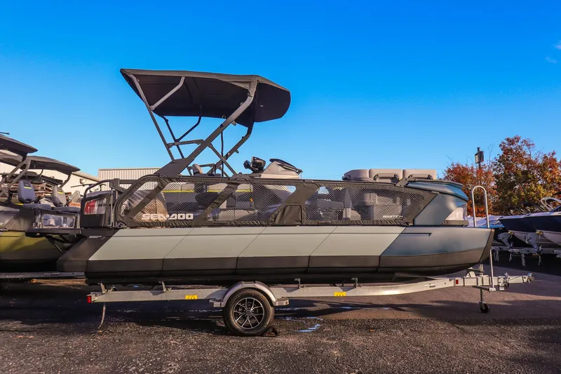 Slide: The Image of 2025 Sea-Doo Switch Cruise Limited 21 pontoon boat on trailer, under clear blue sky. - 1