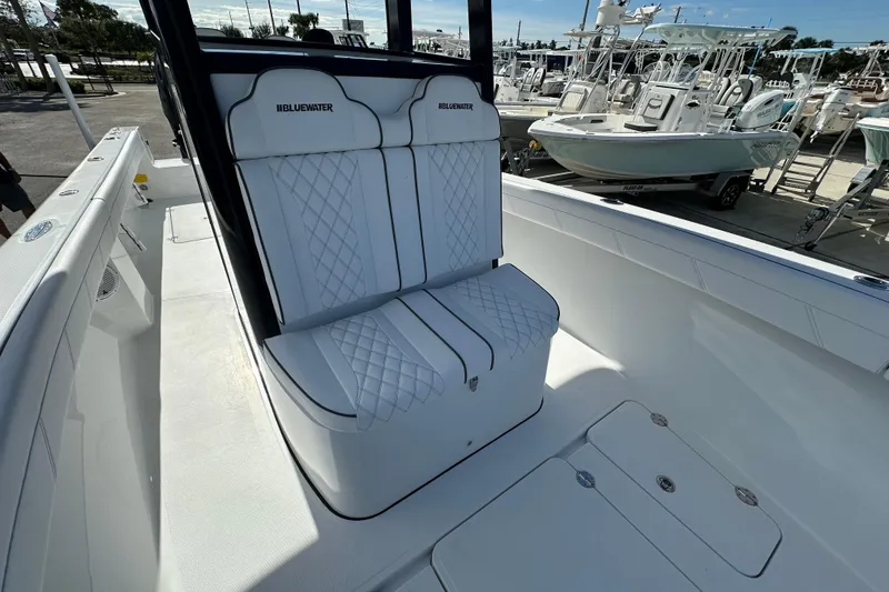 Slide: The Image of 2026 Bluewater 25t boat interior with white quilted seating, docked among other boats. - 12