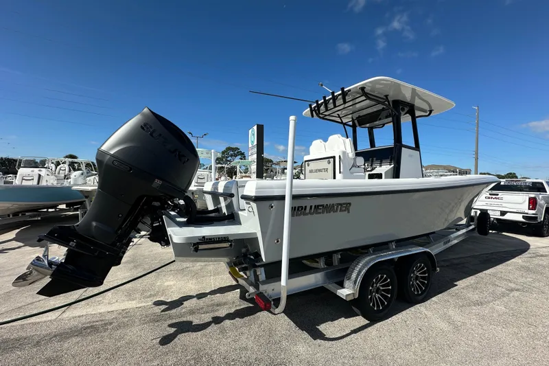 Slide: The Image of 2026 Bluewater 25t boat on trailer with Suzuki outboard motor, parked outdoors. - 2