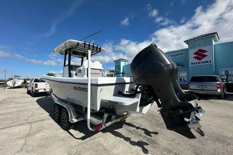Slide: The Image of 2026 Bluewater 25t boat with Suzuki engine parked outside dealership under blue sky. - 4