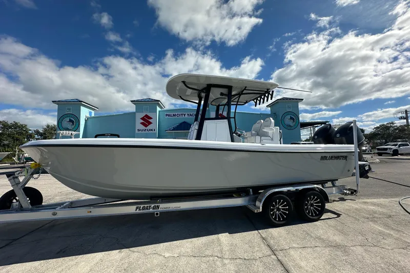 Slide: The Image of 2026 Bluewater 25t boat on trailer at dealership, under a partly cloudy sky. - 5