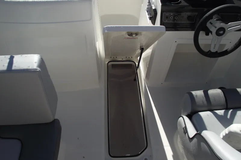 Slide: The Image of 2026 Bayliner VR4 Bowrider OB interior with open storage compartment and steering wheel. - 19