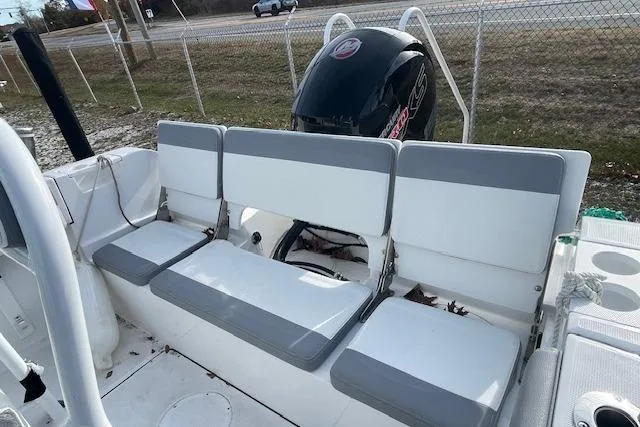 Slide: The Image of 2021 Release 210 RX boat with seating and outboard motor, parked near a fence. - 10