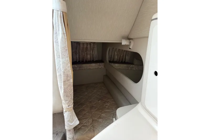 Slide: The Image of 1996 Sea Ray 270 Sundancer cabin interior with bed and curtains. - 18