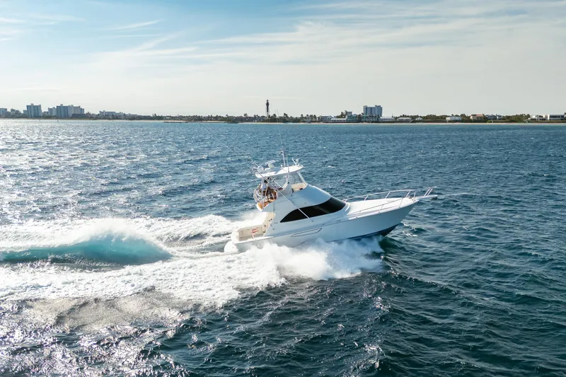 Slide: The Image of 2008 Viking 42 Convertible yacht cruising on open sea near city skyline. - 16