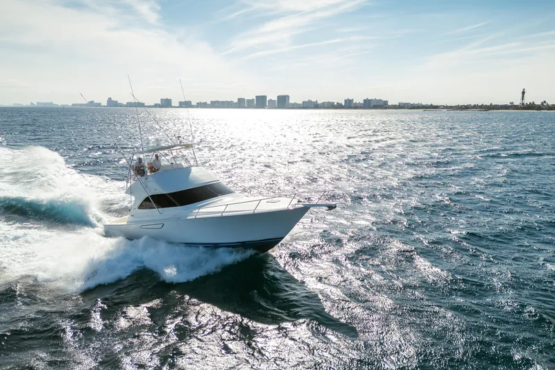 Slide: The Image of 2008 Viking 42 Convertible yacht cruising on open water with city skyline backdrop. - 18