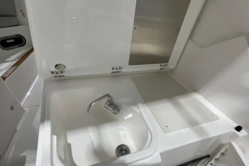 Slide: The Image of 2024 Pursuit DC 326 Dual Console boat sink and faucet in white interior. - 25