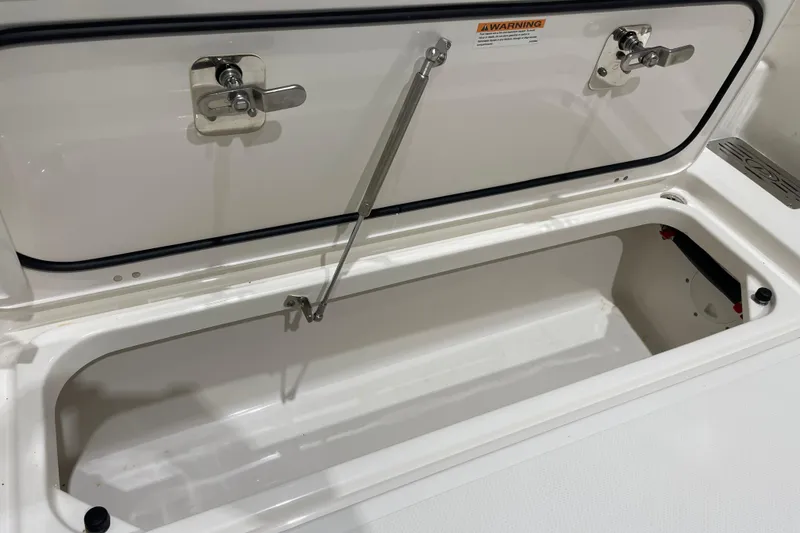 Slide: The Image of 2024 Pursuit DC 326 Dual Console storage compartment with secure latches and hydraulic support. - 27