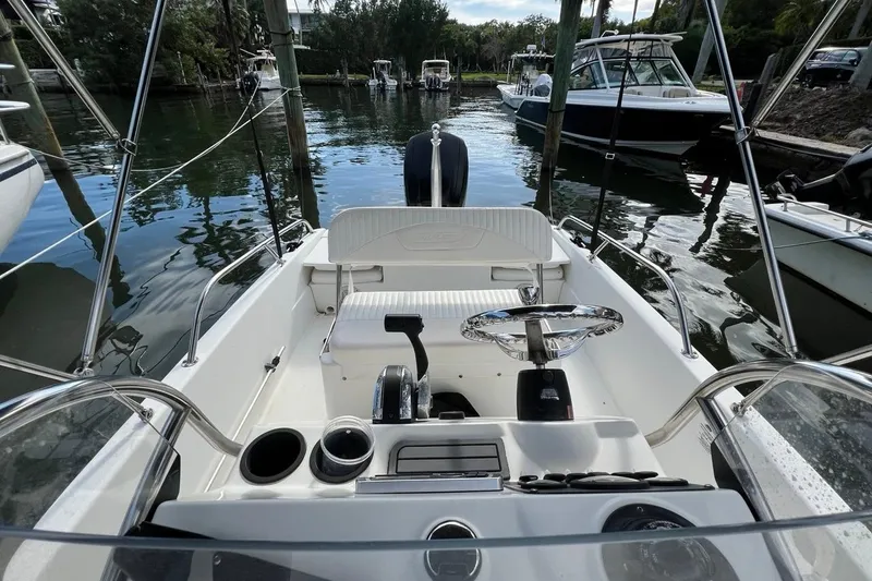 Slide: The Image of 2016 Boston Whaler 170 Dauntless boat interior with steering wheel and seating, docked by the water. - 11
