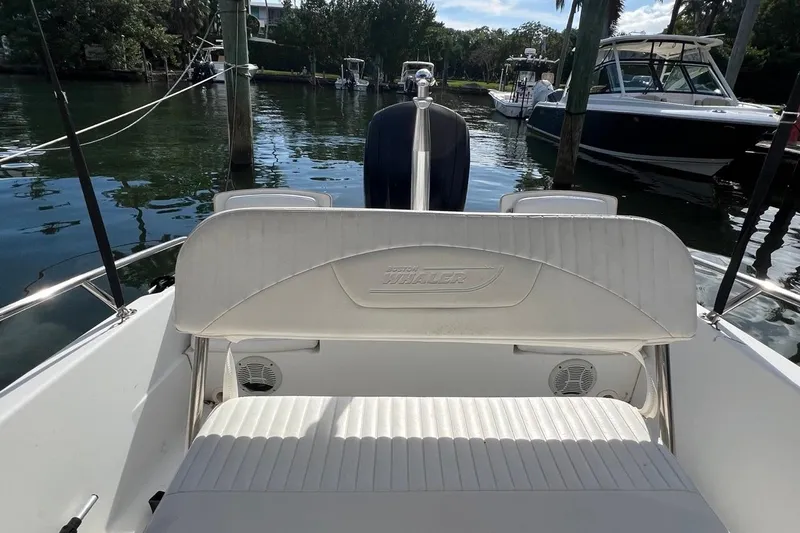Slide: The Image of 2016 Boston Whaler 170 Dauntless boat interior with seating, docked on calm water. - 13