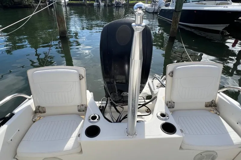 Slide: The Image of 2016 Boston Whaler 170 Dauntless boat interior with seating and motor, docked on calm water. - 15