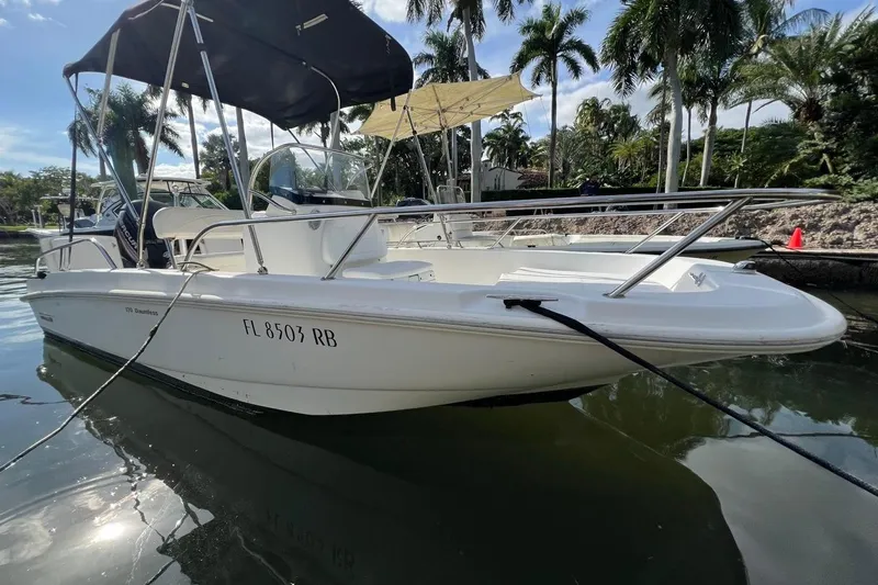Slide: The Image of 2016 Boston Whaler 170 Dauntless boat docked near palm trees. - 2