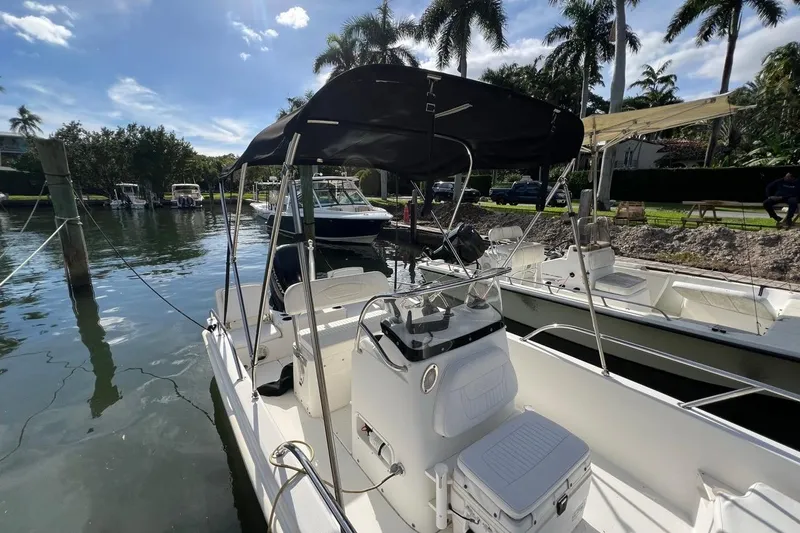 Slide: The Image of 2016 Boston Whaler 170 Dauntless boat docked by palm trees under a sunny sky. - 3