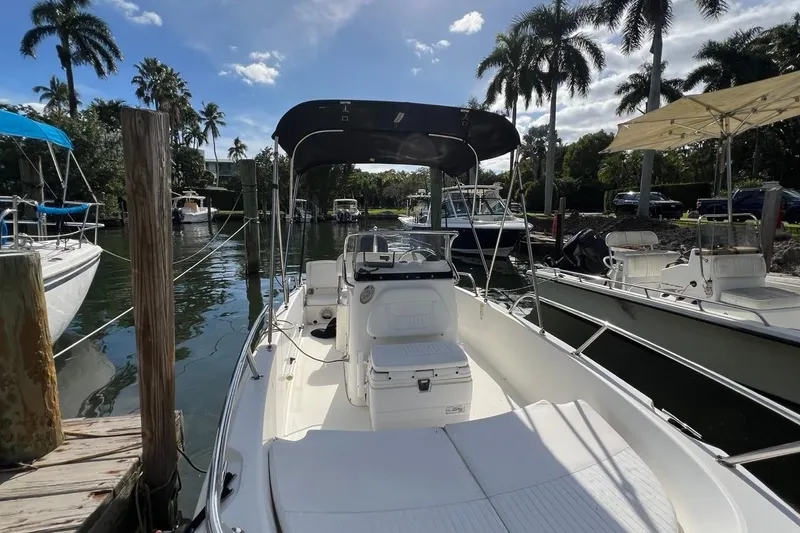 Slide: The Image of 2016 Boston Whaler 170 Dauntless boat docked, surrounded by palm trees and calm water. - 4