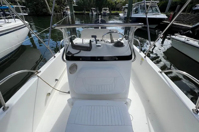 Slide: The Image of 2016 Boston Whaler 170 Dauntless boat interior with steering console, docked in marina. - 7