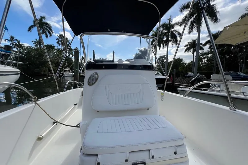 Slide: The Image of 2016 Boston Whaler 170 Dauntless boat interior with seating, under a blue sky and palm trees. - 8