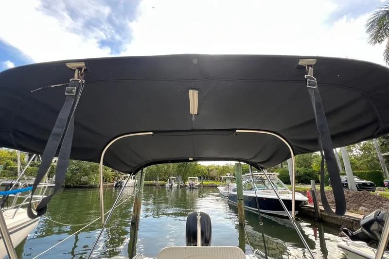 Slide: The Image of 2016 Boston Whaler 170 Dauntless boat with canopy, docked in a scenic marina. - 9