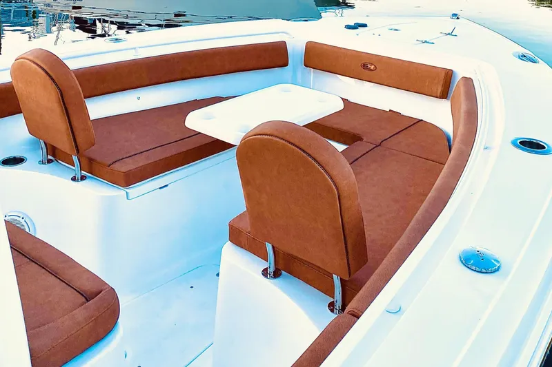 Slide: The Image of 2021 Sea Hunt Ultra 265 SE boat with brown cushioned seating and white table. - 18