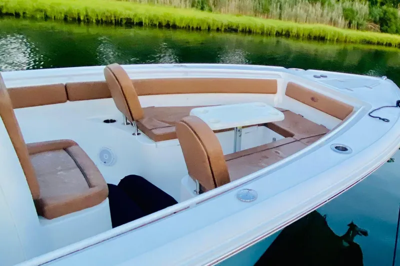 Slide: The Image of 2021 Sea Hunt Ultra 265 SE boat interior with seating and table on calm water. - 19