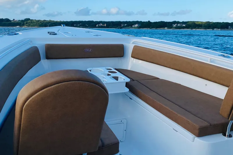 Slide: The Image of 2021 Sea Hunt Ultra 265 SE boat interior with brown seating, on calm water. - 21