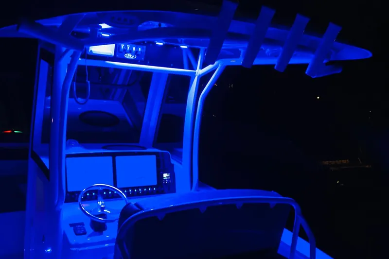 Slide: The Image of 2021 Sea Hunt Ultra 265 SE boat console illuminated with blue LED lights at night. - 27