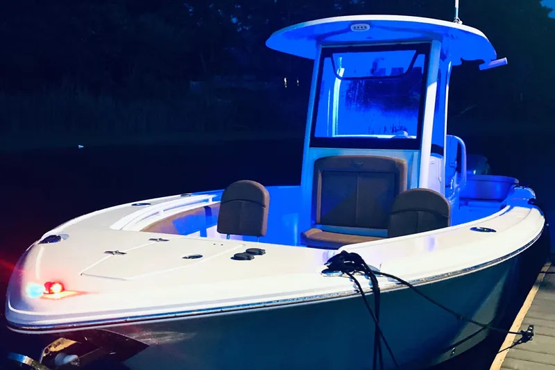 Slide: The Image of 2021 Sea Hunt Ultra 265 SE boat docked at night with blue interior lighting. - 28