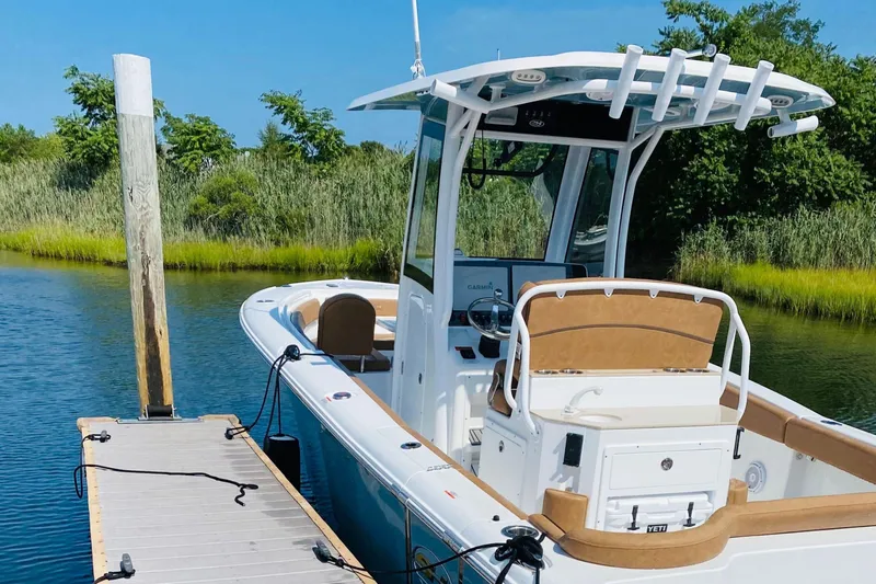 Slide: The Image of 2021 Sea Hunt Ultra 265 SE boat docked by lush greenery. - 3