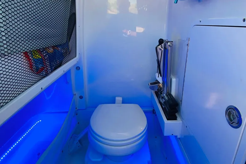 Slide: The Image of 2021 Sea Hunt Ultra 265 SE boat interior with toilet and blue LED lighting. - 33